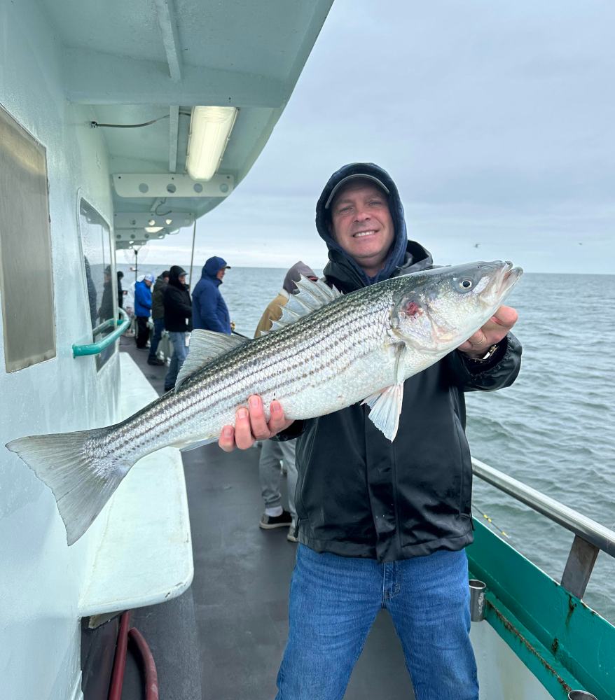 a person holding a fish on a boat posing for the camera