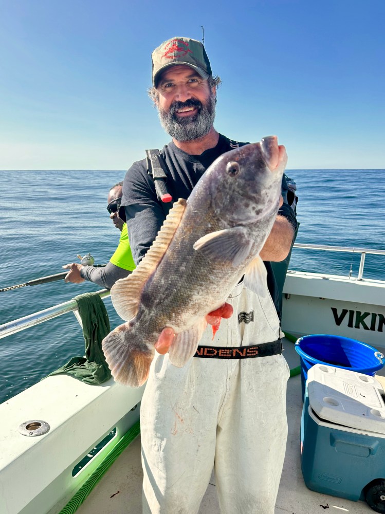 a man holding a fish on a boat in the water