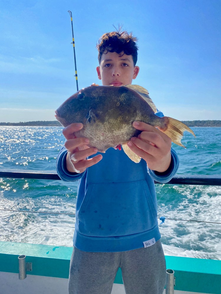 a person holding a fish in front of a body of water