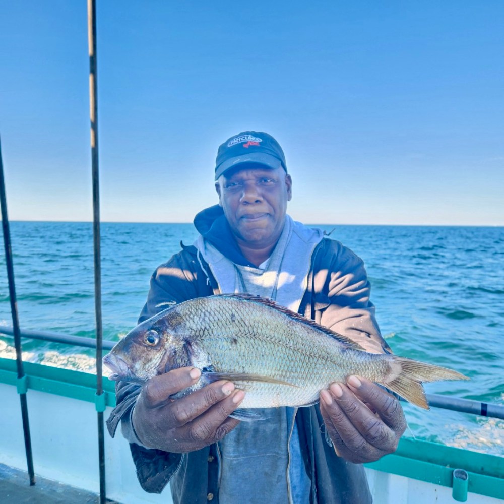 a person holding a fish on a boat in a body of water