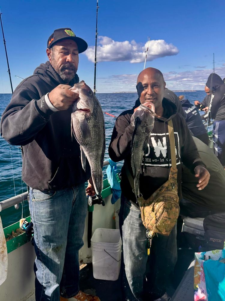 a group of people standing next to a man holding a fish