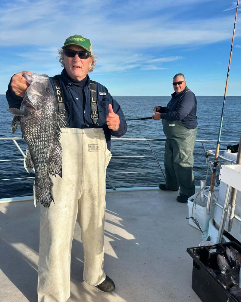 a group of people standing next to a person holding a fish