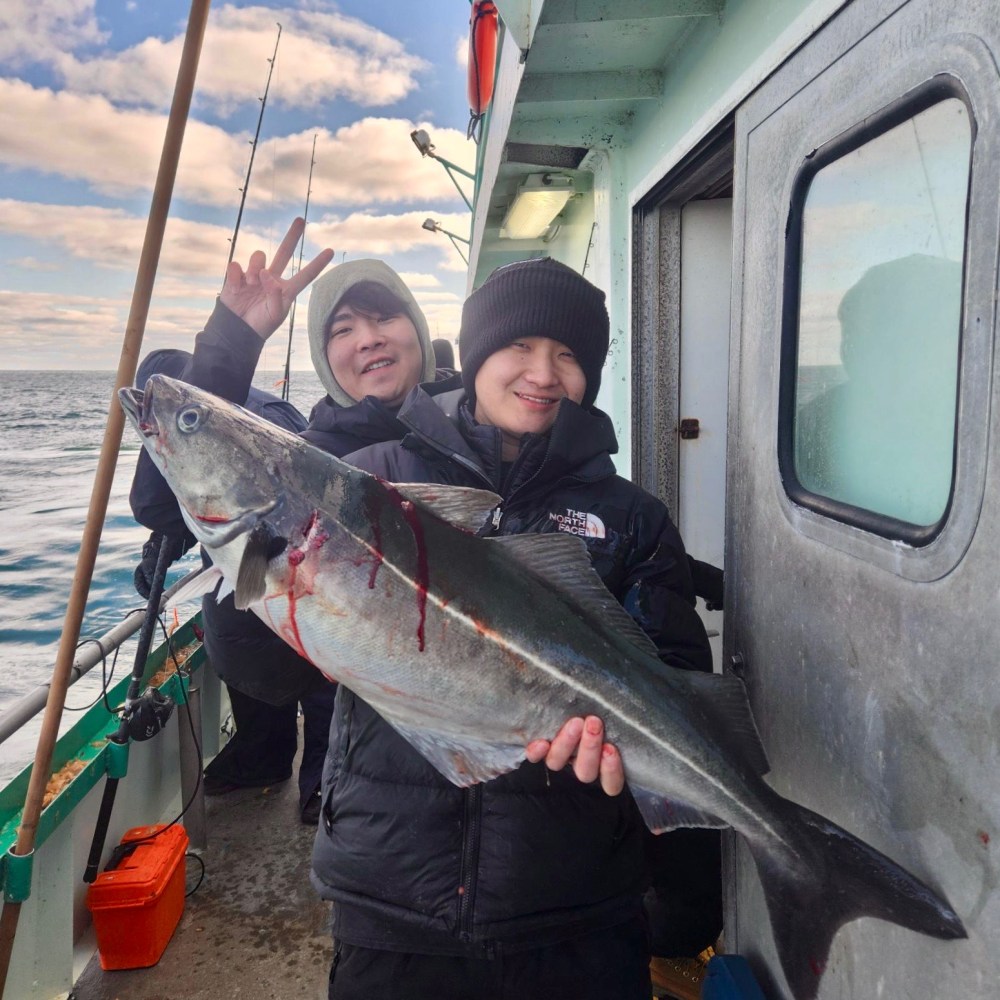 a man holding a fish on a boat posing for the camera