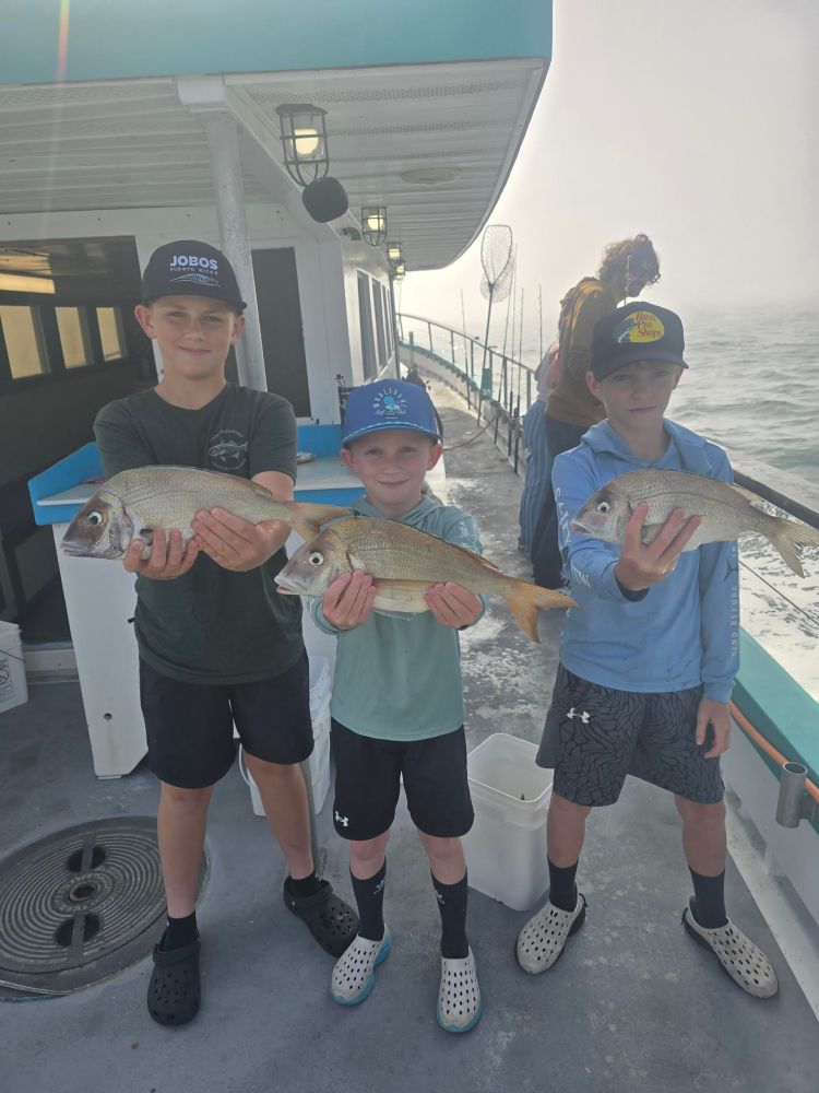 a group of people standing next to a person holding a fish
