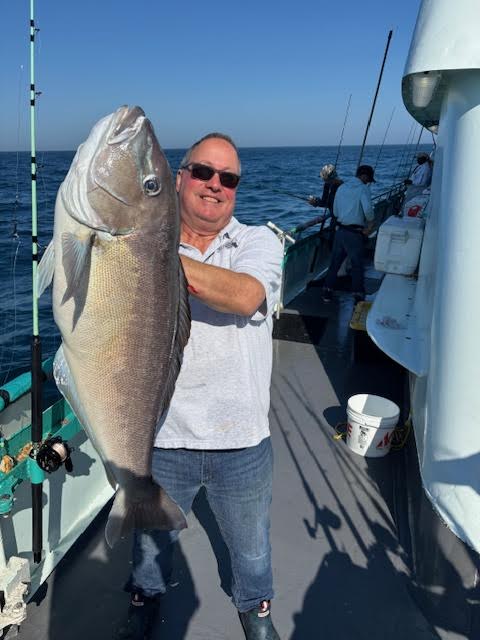 a man holding a fish on a boat
