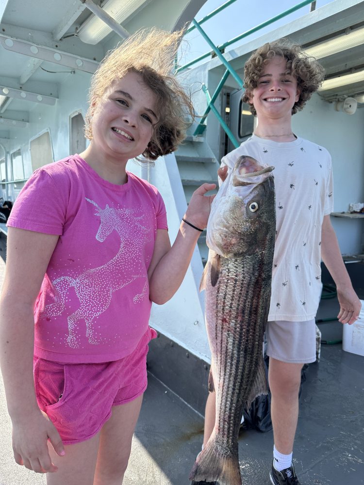 a group of people standing next to a person holding a fish