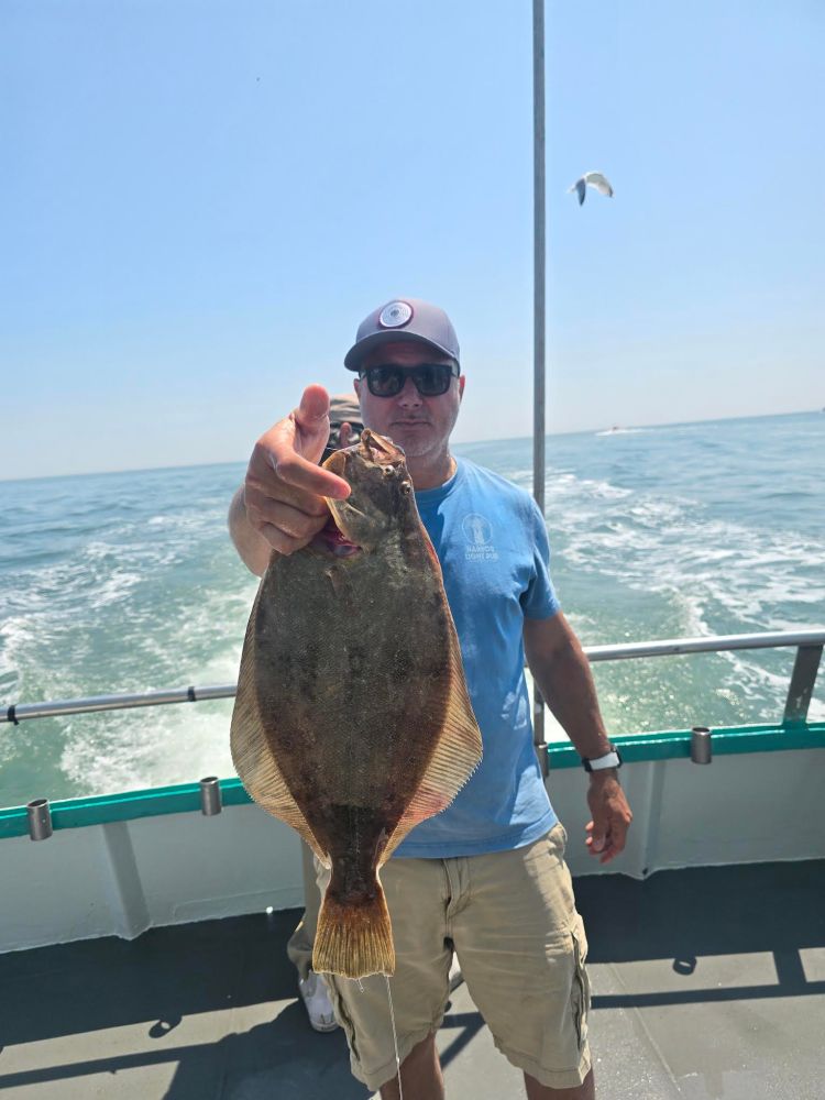 a man holding a fish on a boat in the water