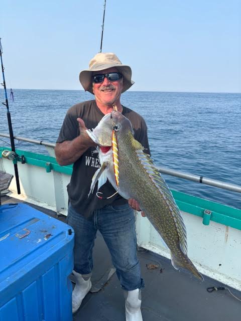 a person holding a fish on a boat in a body of water
