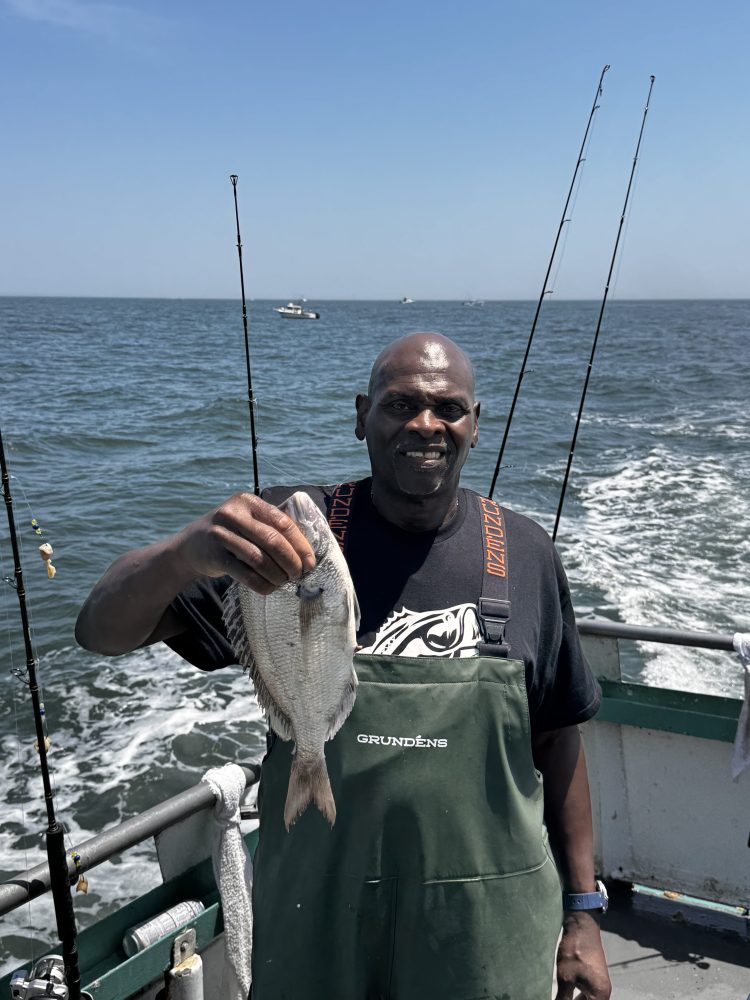 a man holding a fish on a boat in a body of water