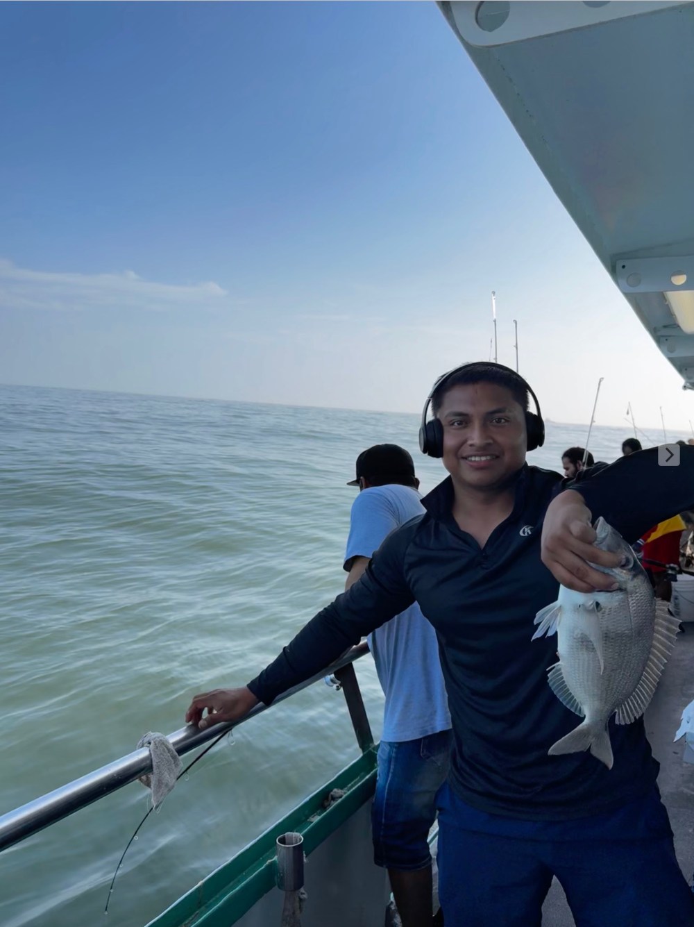 a person standing in front of a boat next to a body of water