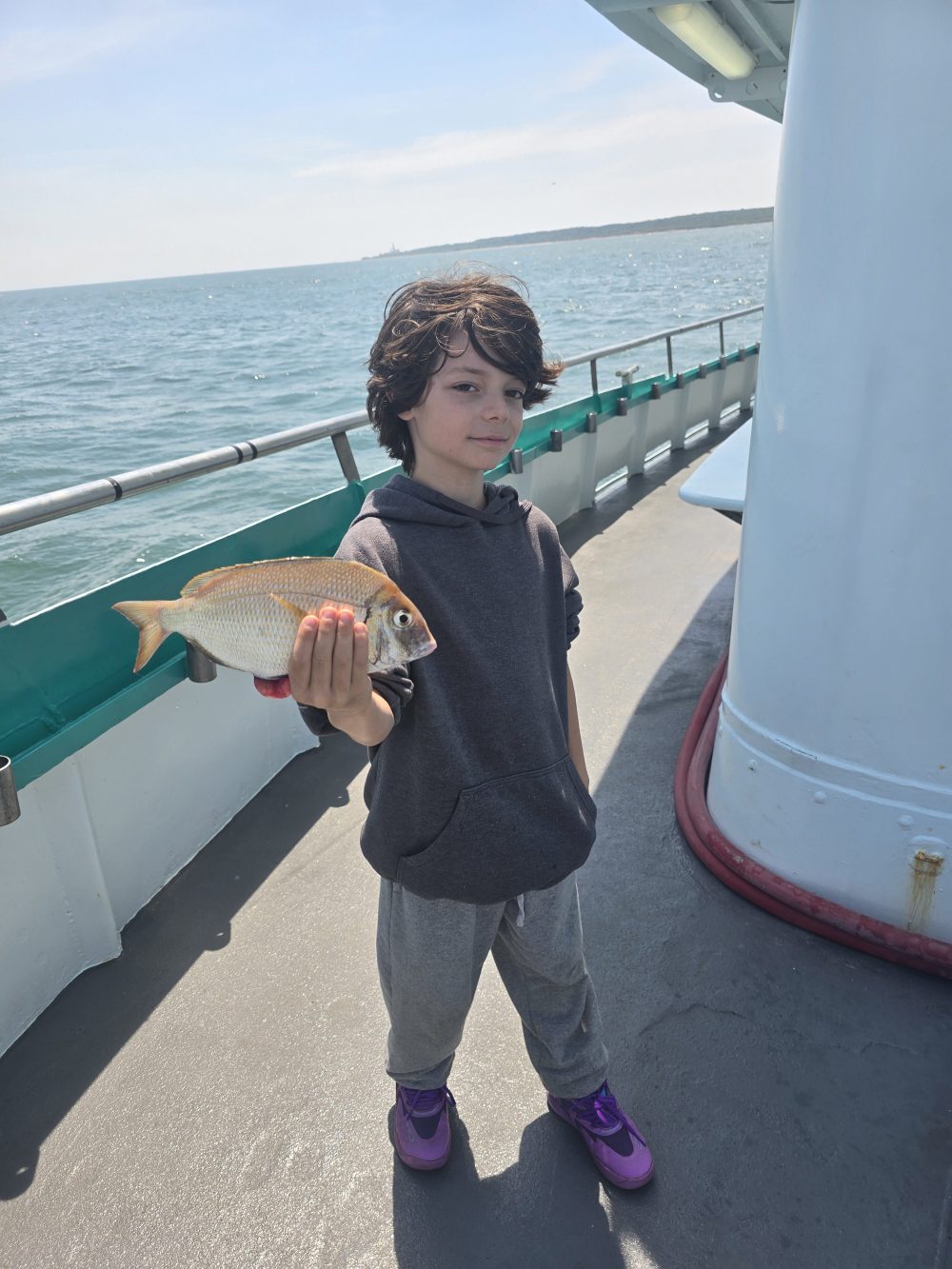 a little boy standing next to a body of water