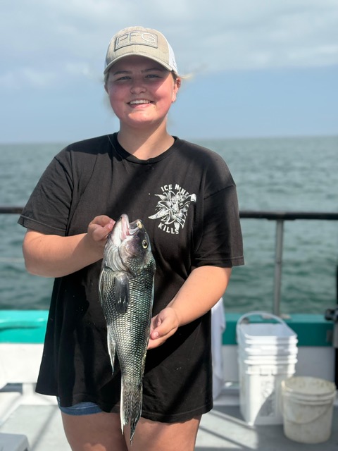 a person holding a fish in front of a body of water
