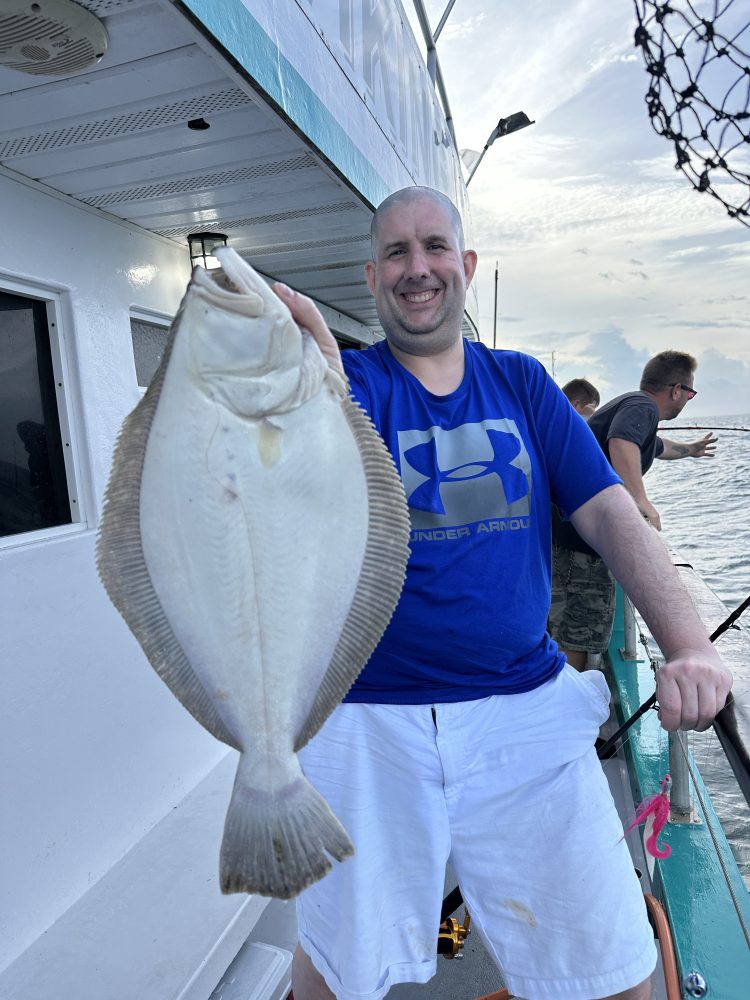 a person holding a fish posing for the camera