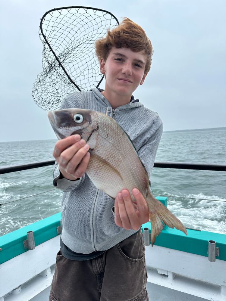 a person holding a fish on a boat in a body of water