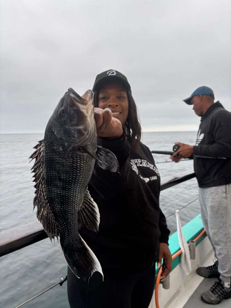 Person holding a fish on a boat, with another person in the background.