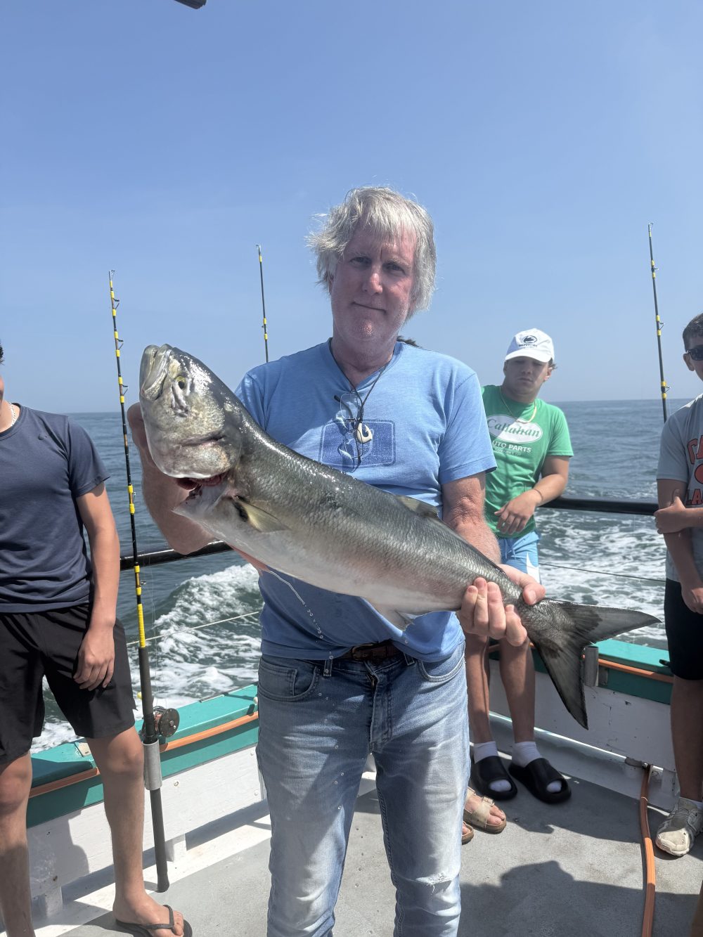 Person on boat holding a large fish with ocean in the background.