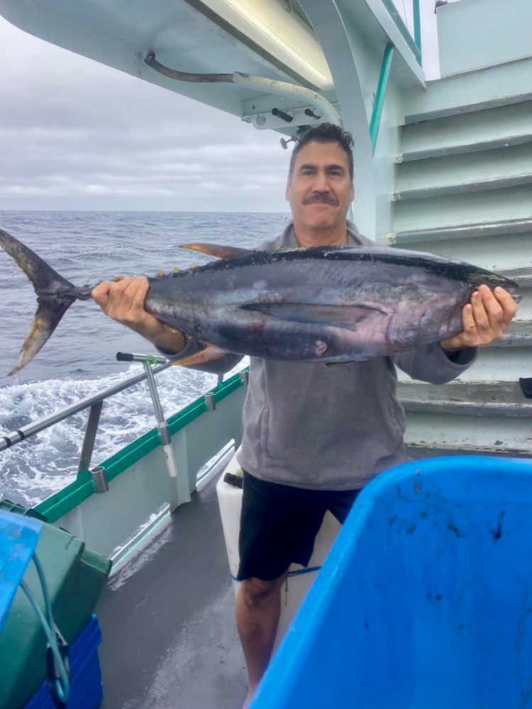 Person holding a large fish on a boat with the ocean in the background.