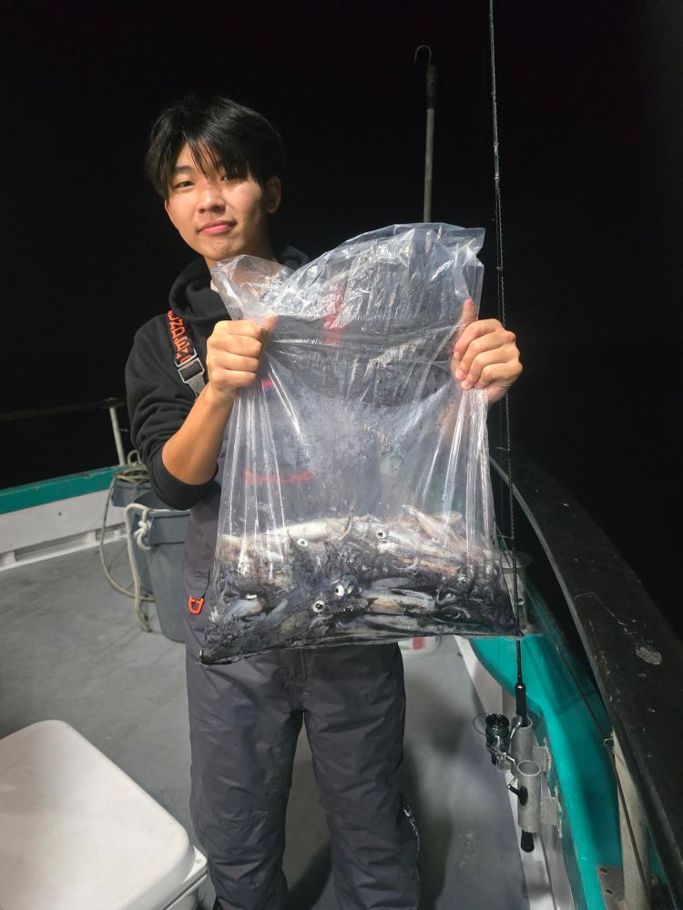 Person on a boat holding a large bag of fish at night.