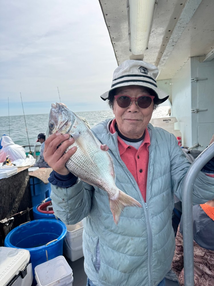Person holding a fish on a boat, wearing a bucket hat and sunglasses.