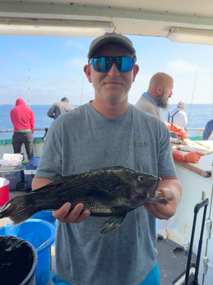 Person holding a large fish on a boat with people in the background.