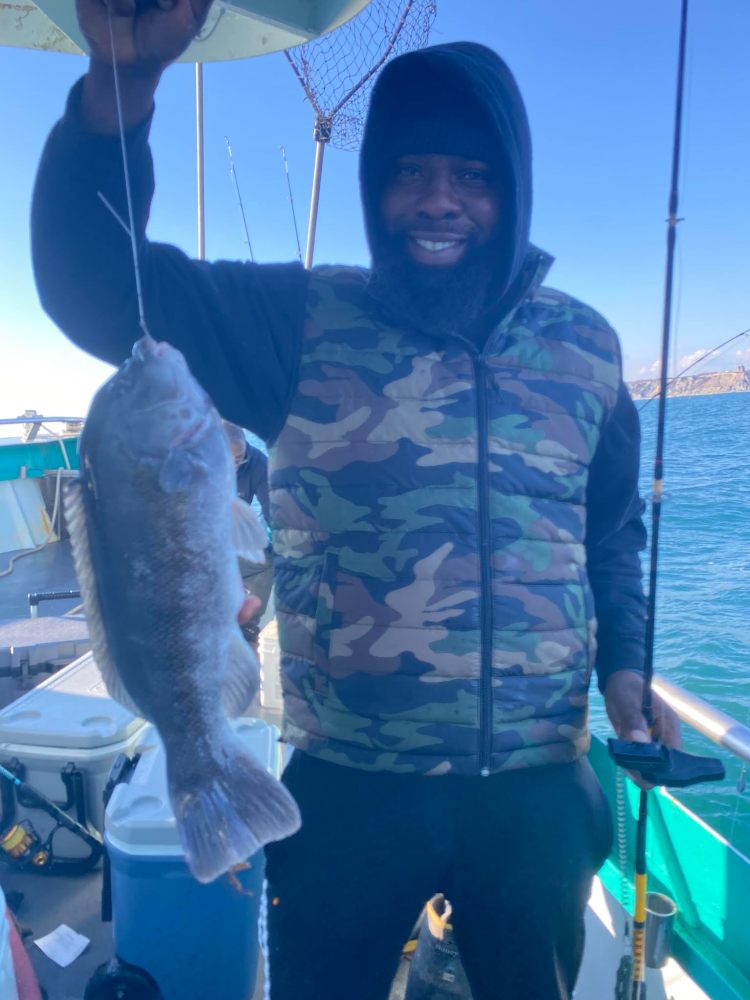 Person in camouflage jacket holding a fish on a boat.