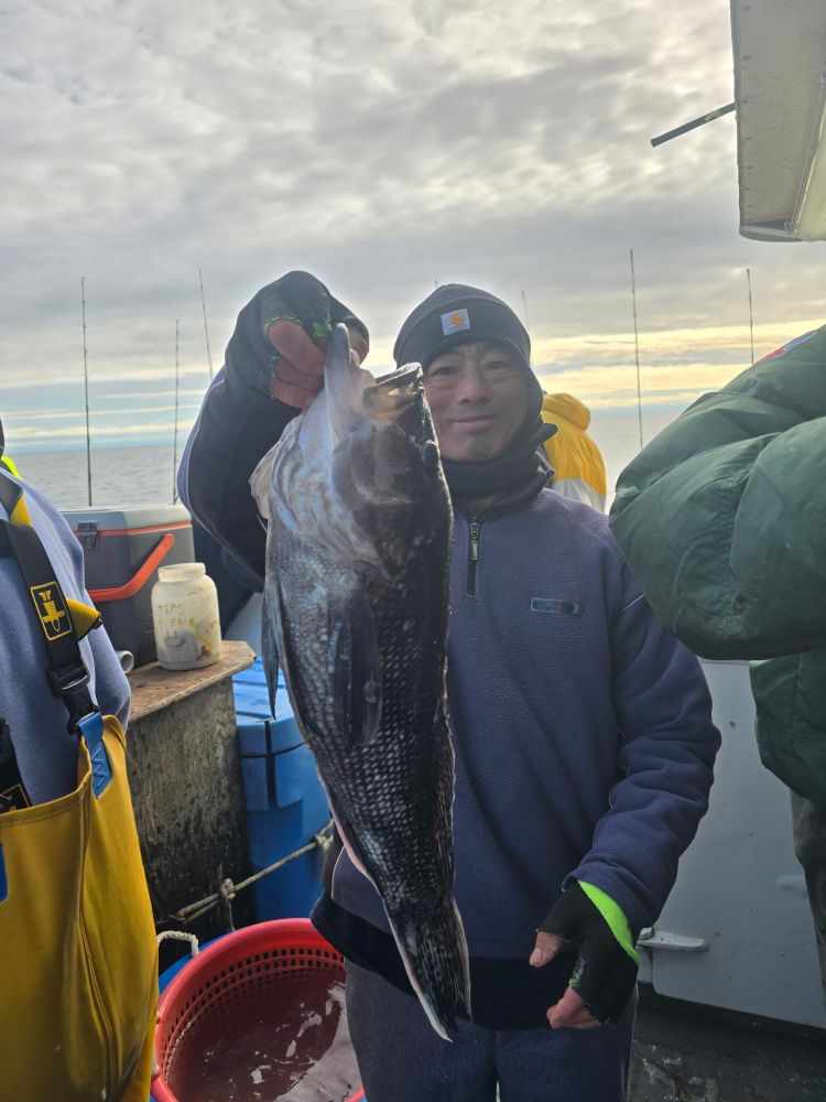 Person holding a large fish on a boat under a cloudy sky.