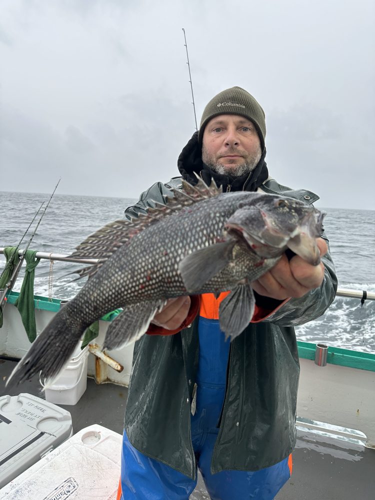 Person in winter gear holding a large fish on a boat.