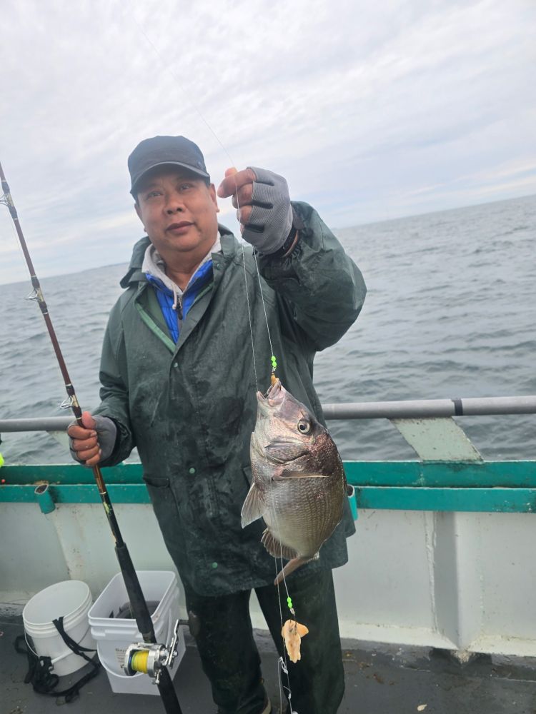 Person in raincoat holding fishing rod and fish on boat.