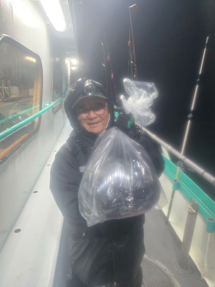 Person on a boat holding a plastic bag with fishing rods at night.