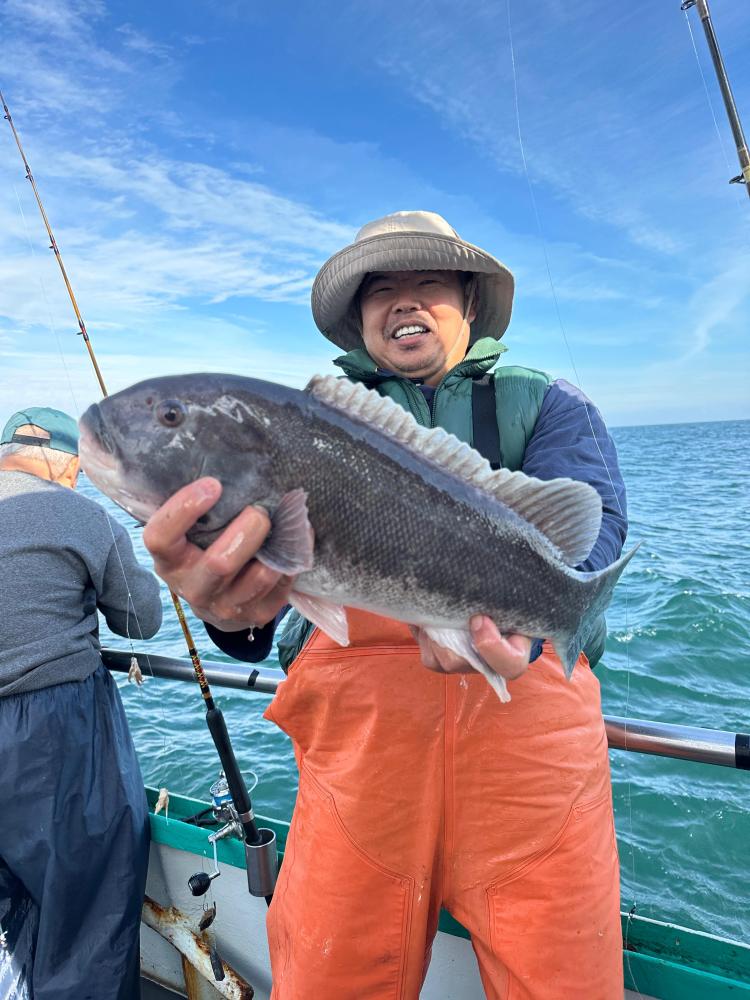 Person on boat holding a large fish with ocean and sky in the background.
