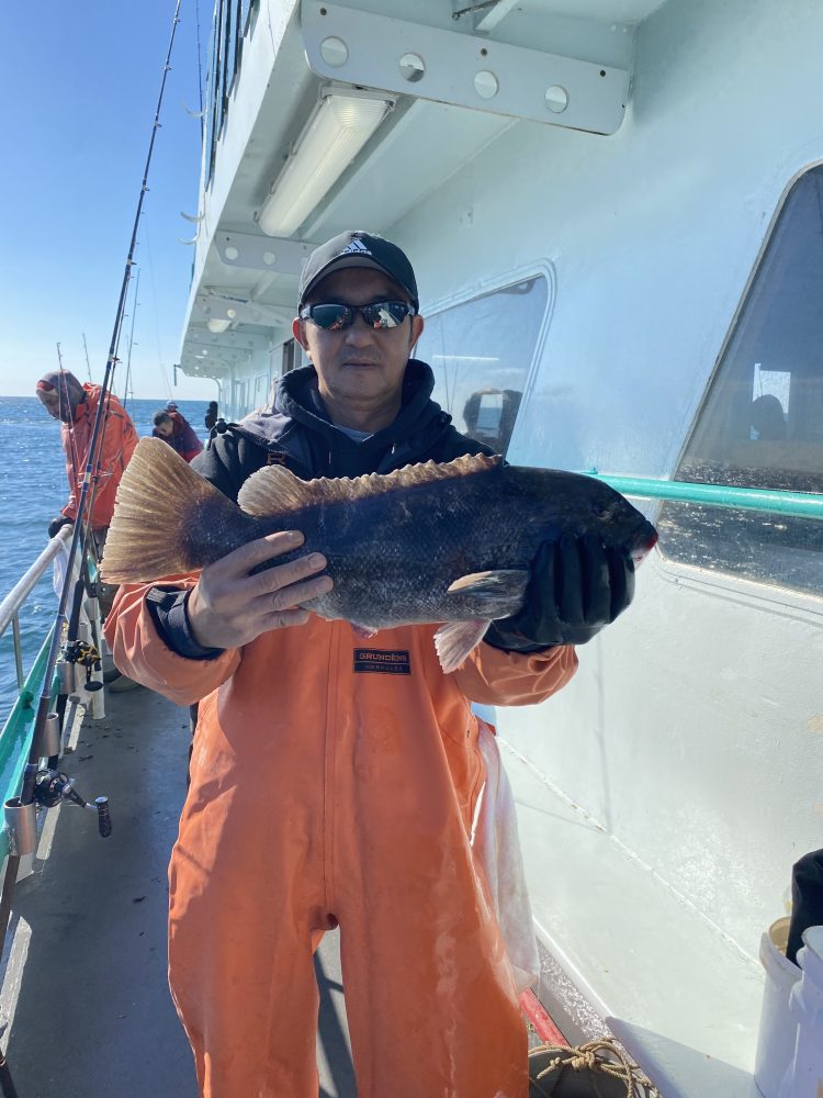 Person in orange overalls holding a fish on a boat.
