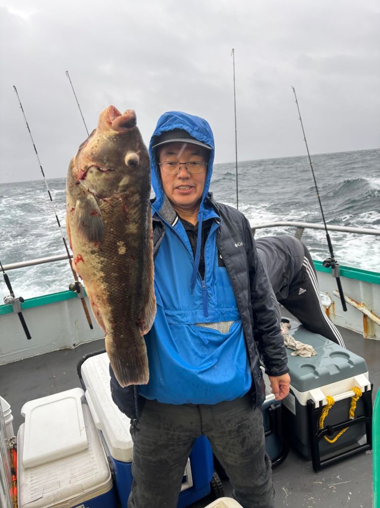 Person on a boat holding a large fish with an overcast sea backdrop.