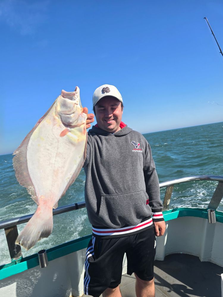 Person holding a large fish on a boat in the ocean.