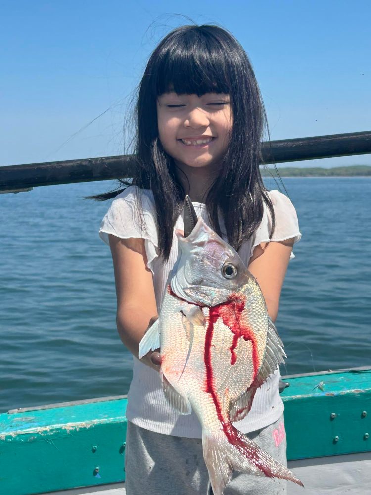 Smiling girl holding a freshly caught fish on a boat.
