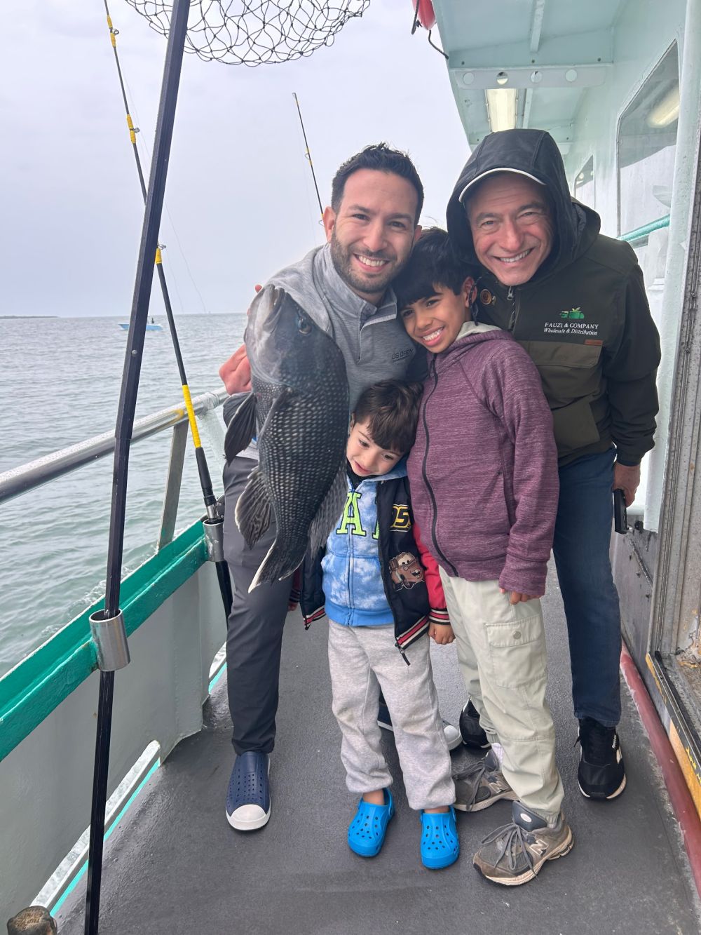 Three people smiling on a boat holding a large fish.