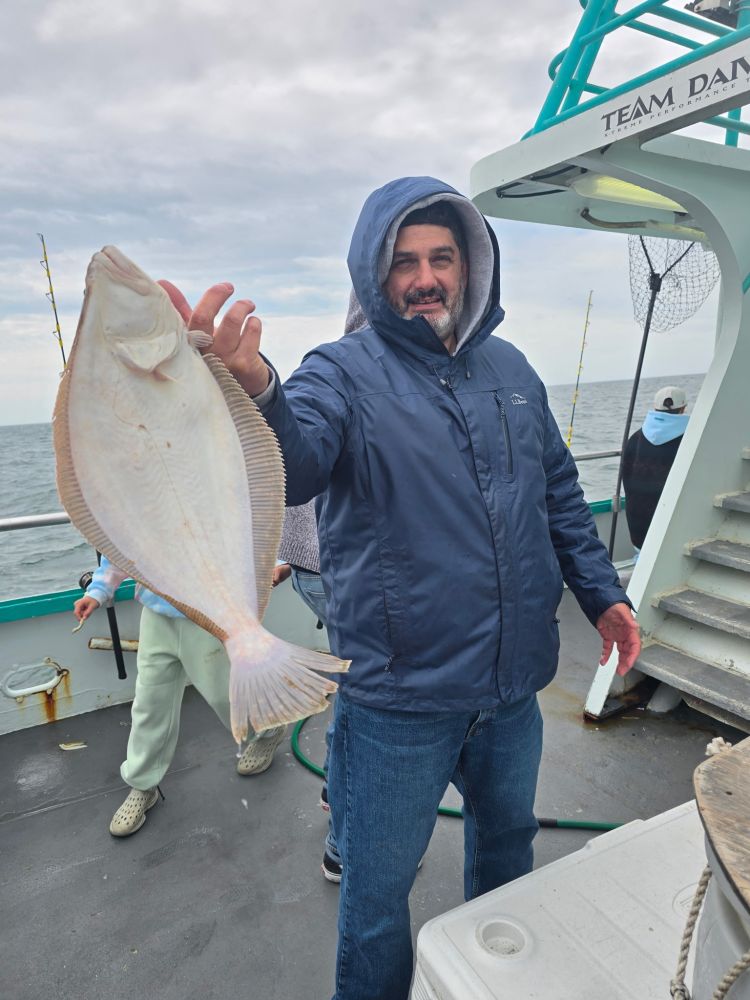 Person on boat holds a large fish on a cloudy day.