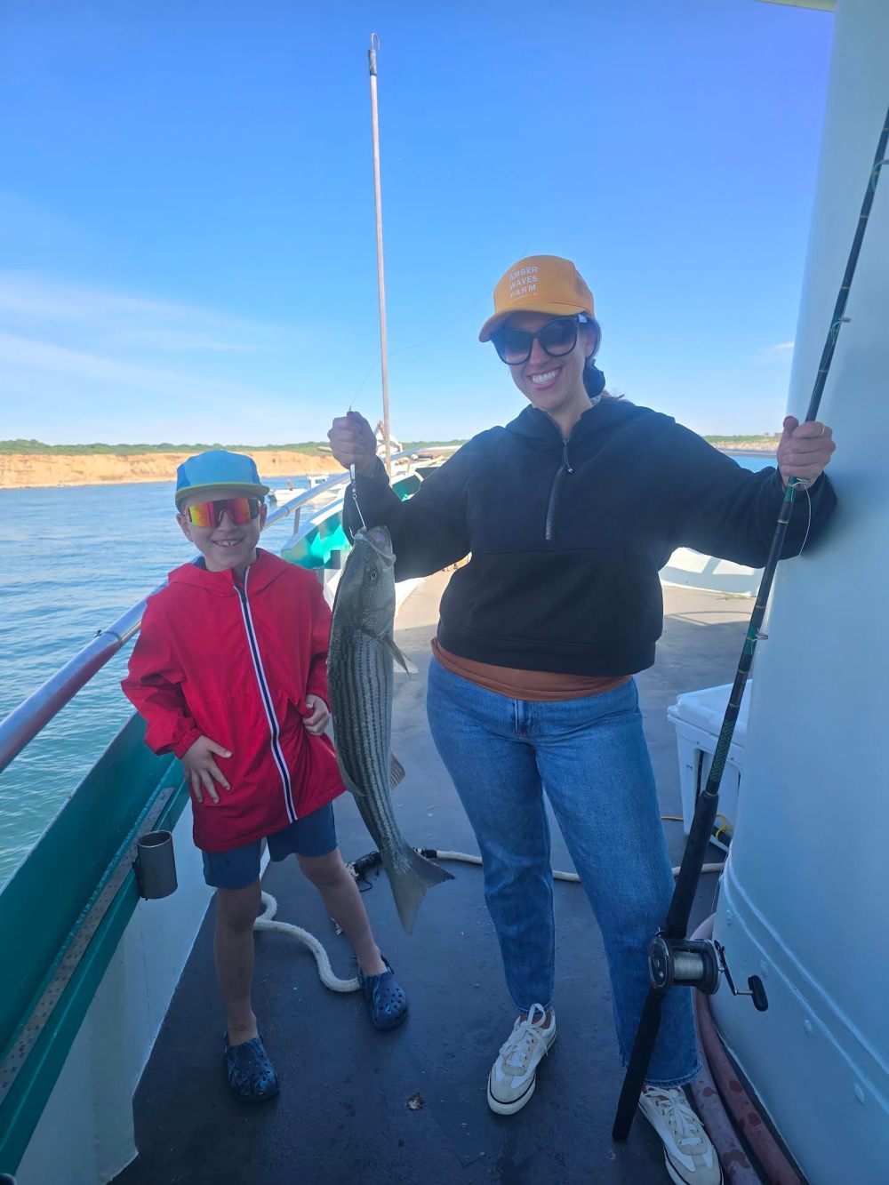 Woman and child on a boat holding a fish, smiling.