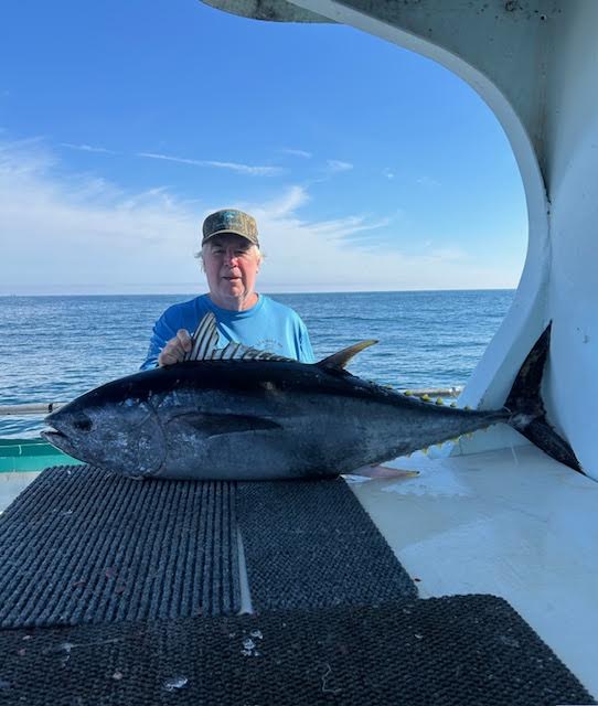 Person on boat holding a large fish with ocean in background.