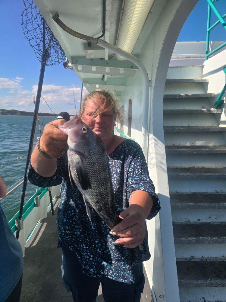 Person holding a fish on a boat deck with a staircase in the background.