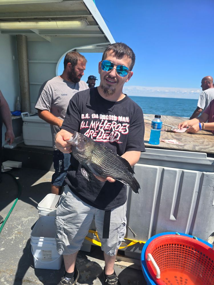 Person holding a fish on a boat with people in the background.