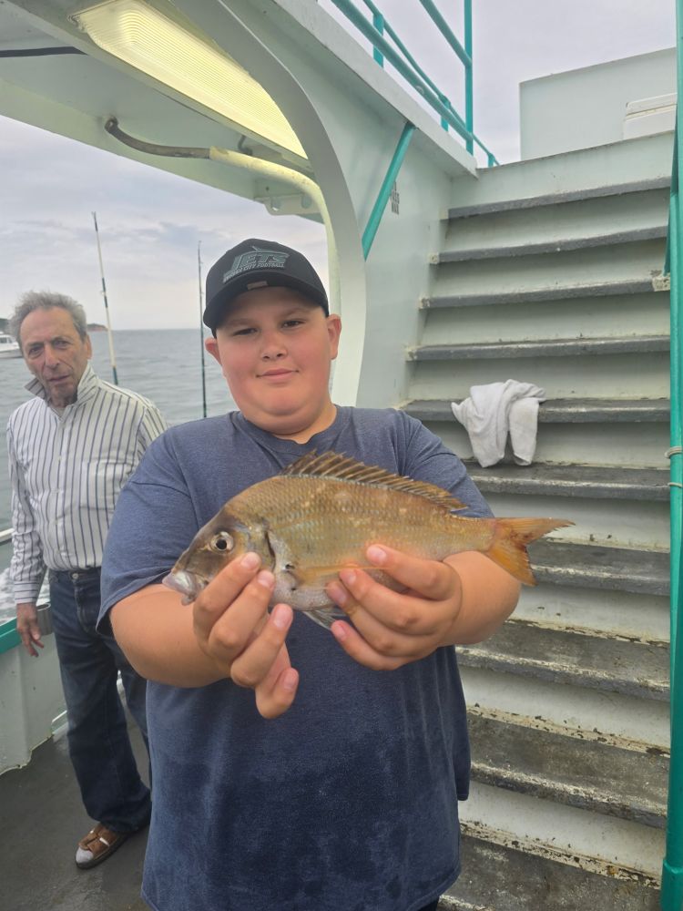 Child holding a fish on a boat with stairs in the background.