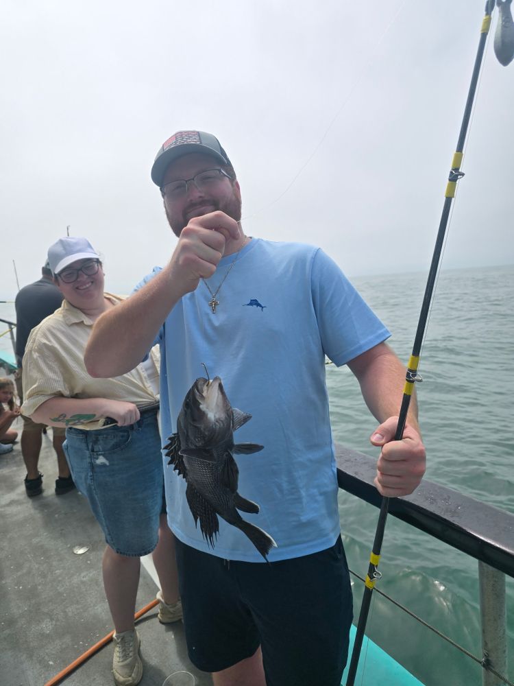 Two people on a boat, one holding a fishing rod and fish.
