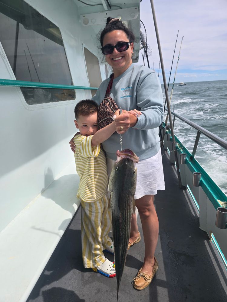 Woman and child on boat holding a large fish.