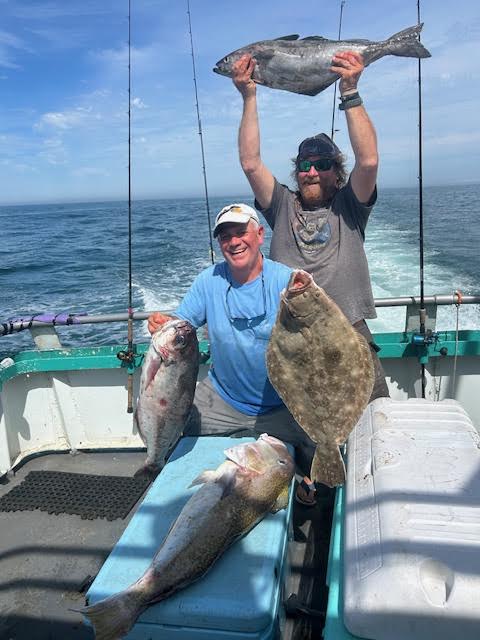 Two men on a boat holding large fish they caught.