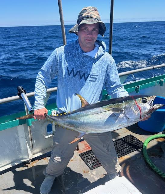 Person holding a large fish on a boat in the ocean.