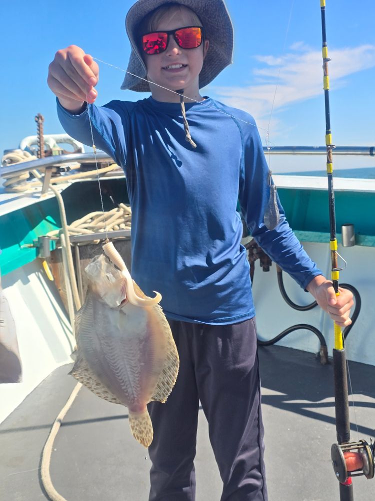 Person holding a fishing rod and a caught fish on a boat.