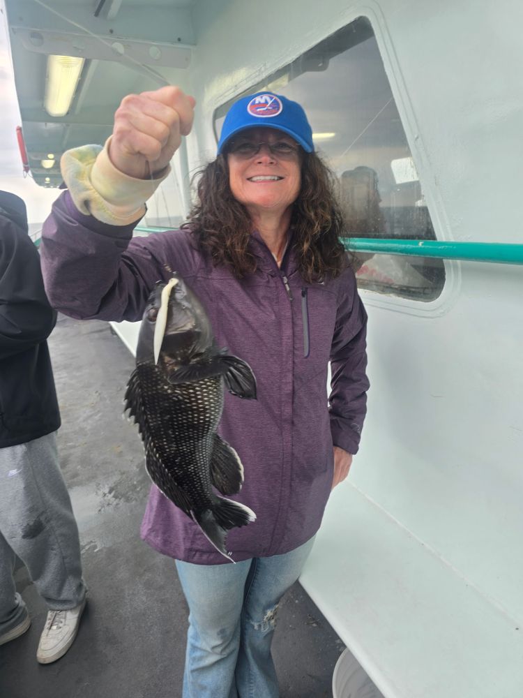 Person smiling, holding a fish on a boat.