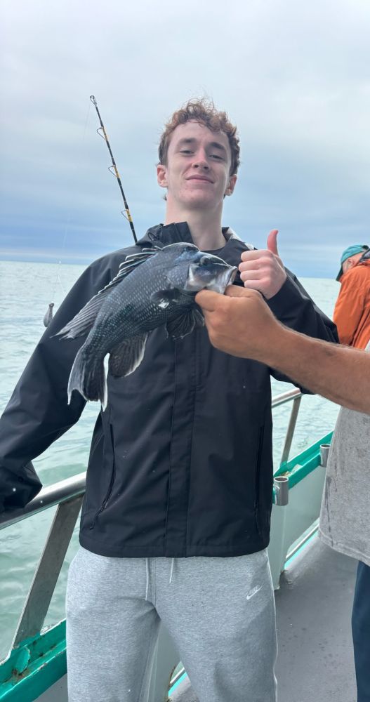 Person on a boat holding a fish and giving a thumbs up.