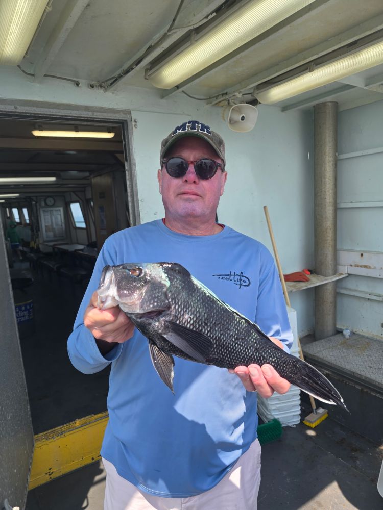 Man holding a large black fish on a boat.