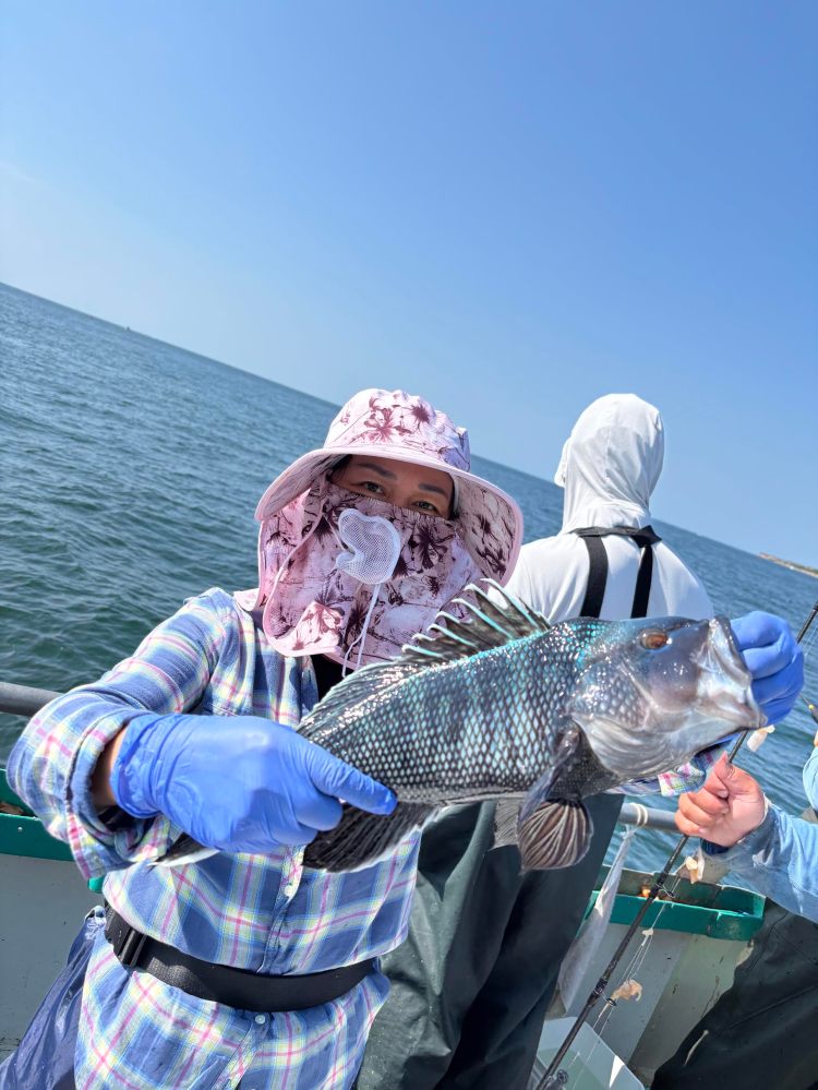 Person holding a fish on a boat wearing sun protection clothing.